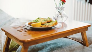 A wooden table with a plate of food and a vase with flowers. - MyTourist (Heumen)