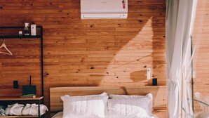 A bedroom with a wooden ceiling, a bed with white bedding, a bedside table with a lamp, and a wall-mounted air conditioner. - MyTourist (Heumen)