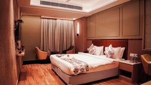 A hotel room with a large bed, a chair, a desk, and a bedside table. - GENX JAMUI (Jamui)