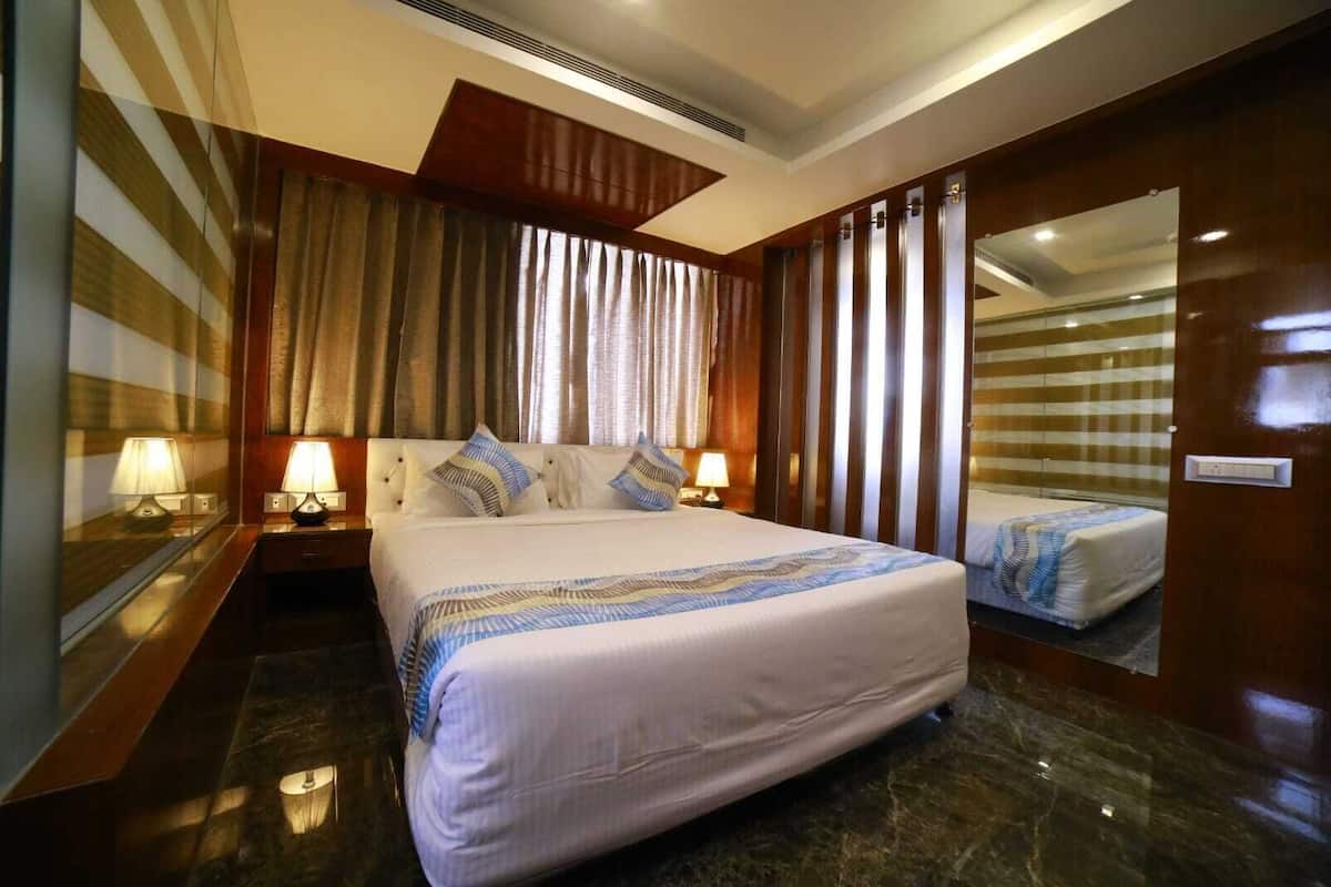 A hotel room with a large bed, two bedside tables with lamps, a mirror, and a view of the room's interior.