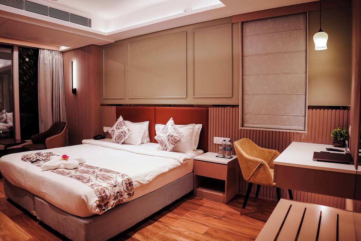 A modern hotel room with a large bed, bedside tables, a desk, and a chair.