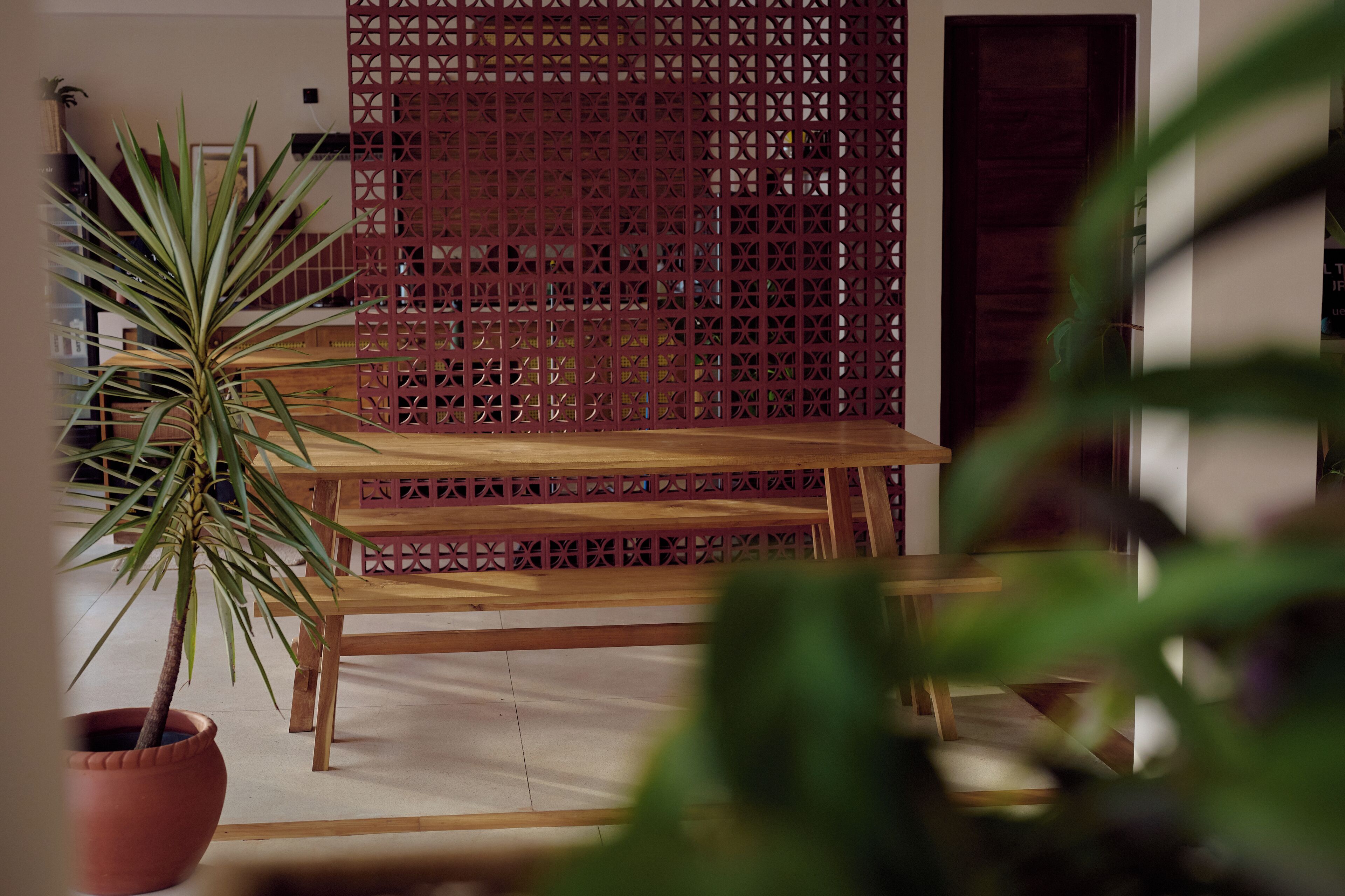A room with a wooden table, a potted plant, and a decorative red lattice partition.