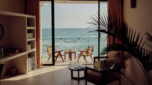 Una stanza con vista sull'oceano, una ventola a soffitto, una libreria e un angolo salotto con sedie e un tavolo.