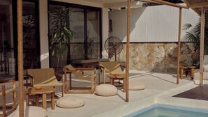 Area piscina all'aperto con lettini, un tavolo e un muro in pietra.