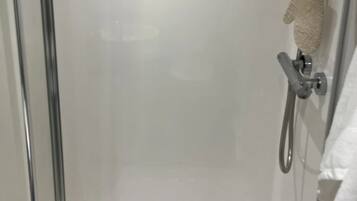 Un baño moderno con cabina de ducha de vidrio, un cabezal de ducha manual y un perchero para toallas.
