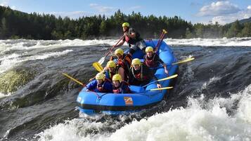 A group of people in a blue raft navigating through a river with rapids.
