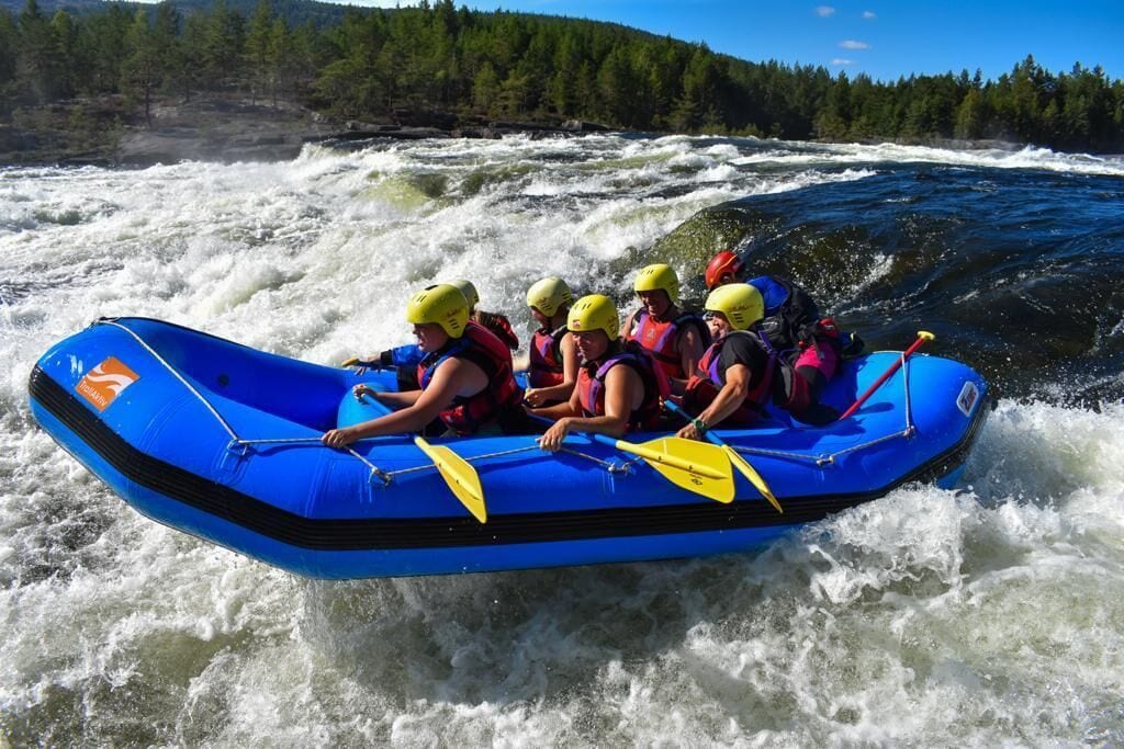 Un grupo de personas en una balsa inflable azul navegando por un río con rápidos blancos.