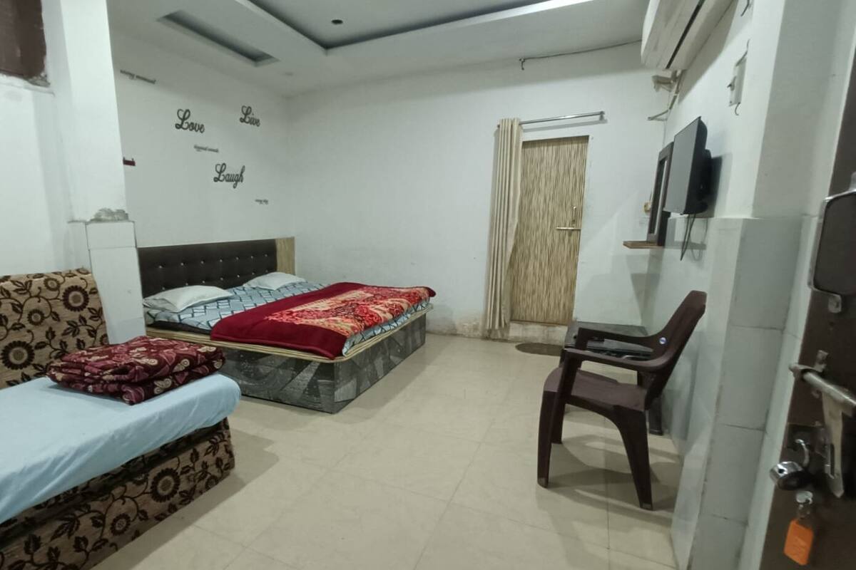 A bedroom with a bed, a sofa, a desk, and a TV.
