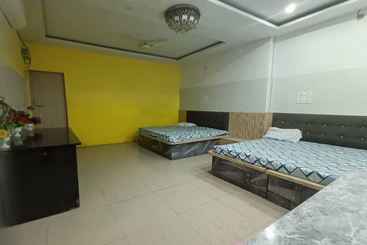 A hotel room with two beds, a desk, and a yellow accent wall.