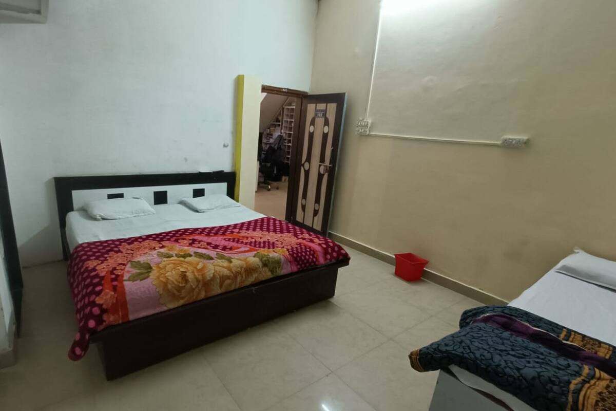 A bedroom with a bed, a wardrobe, a red bucket, and a white cabinet.