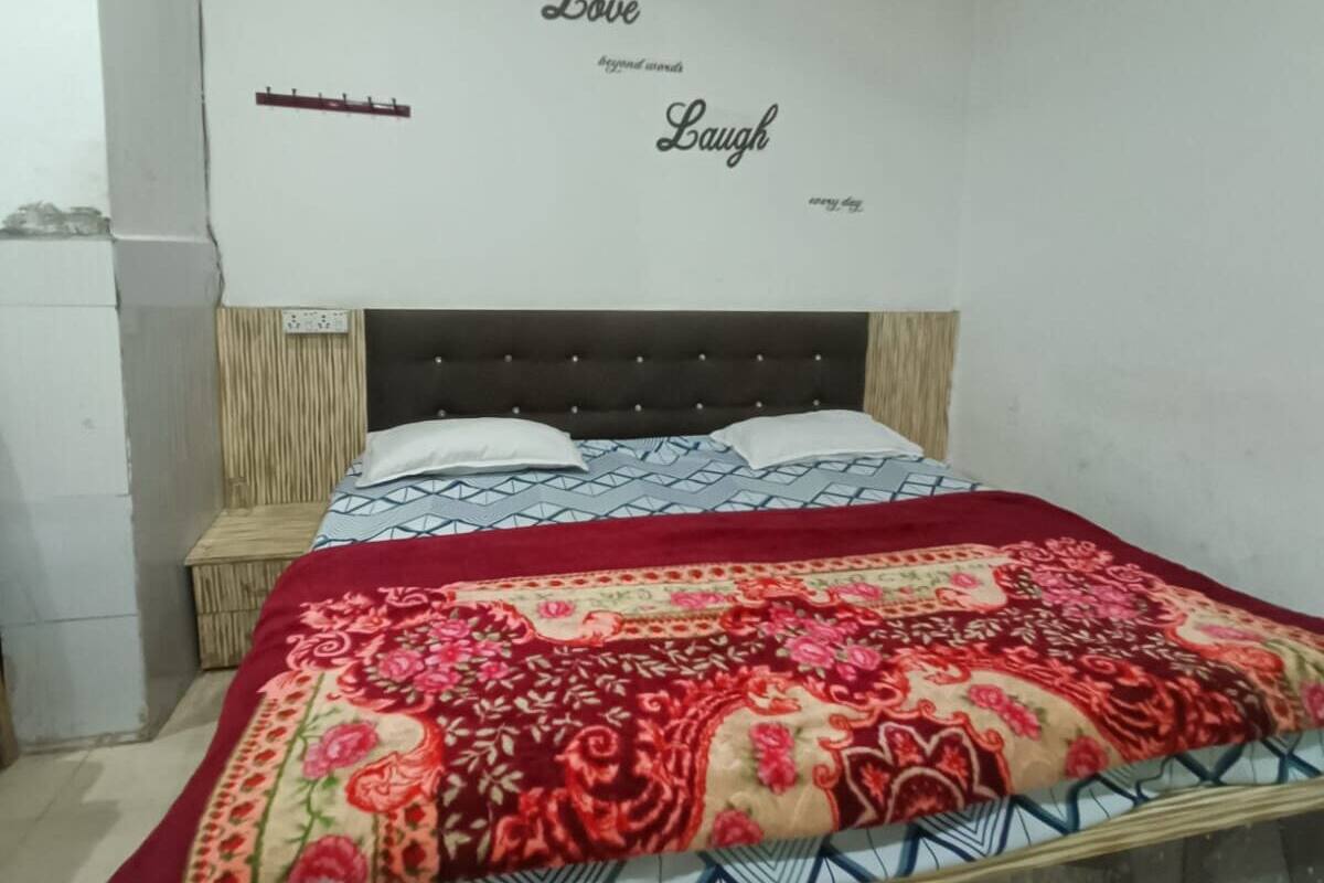 A bedroom with a bed, a headboard, and a wall with motivational phrases.