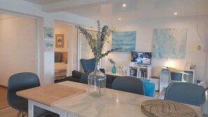 A modern living room with a dining area, a TV, and a bookshelf. - Holiday Home in Porto da Cruz With Garden (Machico)