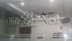 A hotel sign with the name 'Olive Nest' and a logo featuring a house and flowers. - Olive Nest Tirupati (Tirupati)
