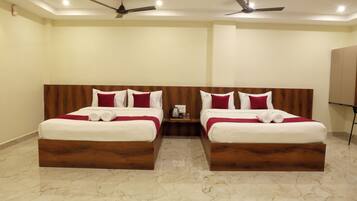 Quarto de hotel com duas camas, piso de mármore, ventiladores de teto e um guarda-roupa.