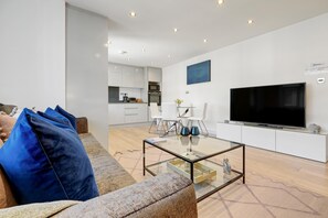 Relax in this stylish living room with a sofa, flat-screen TV, and dining area.