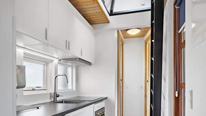 A modern kitchen with white cabinetry, a stainless steel sink, and a built-in oven. - 5 Person Holiday Park Home in Krusa (Krusaa)