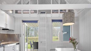 A modern kitchen with a large island, a dining area with a white table, and a view of the outdoors through a door. - 5 Person Holiday Park Home in Krusa (Krusaa)
