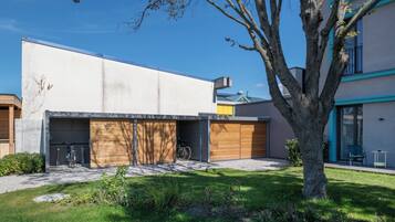 Un bâtiment moderne avec un garage, un vélo et un arbre dans la cour.