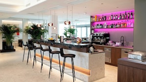 A modern bar area with a bar counter, stools, and a variety of liquor bottles. - Hotel Le Parc (Wiener Neustadt)
