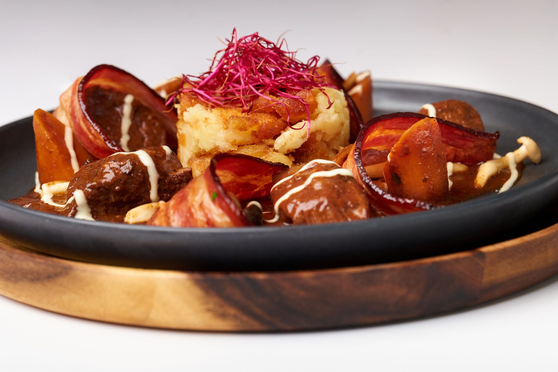 A plate of food with a variety of items including a piece of bread topped with a red garnish, a baked item, and several pieces of meat and vegetables.