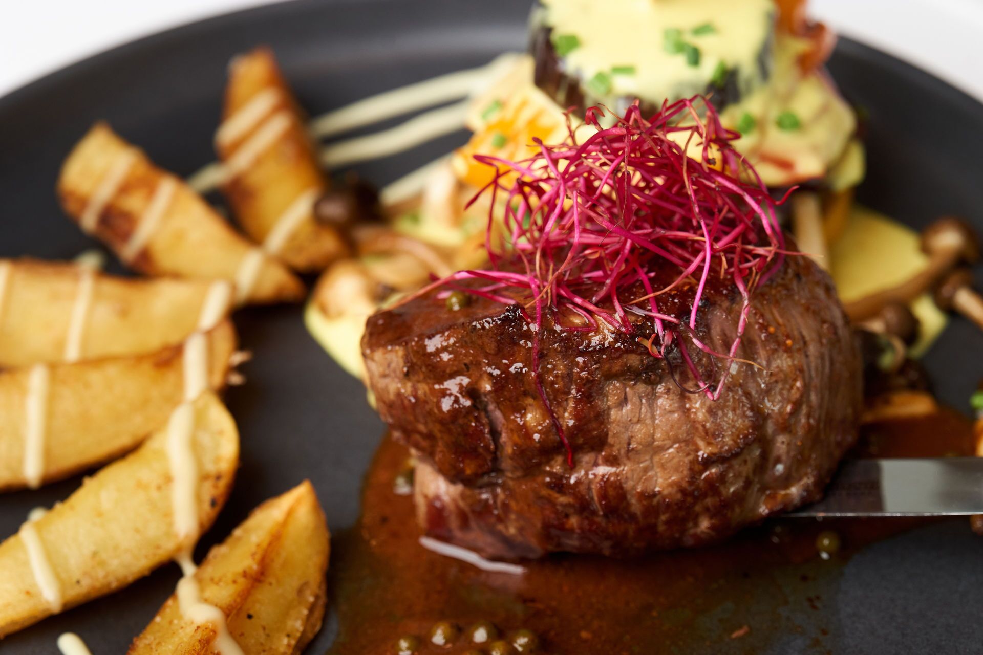 Un steak, accompagné d’une garniture de légumes rouges, servi sur une assiette avec des frites et un autre accompagnement.
