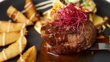 Un steak, accompagné d’une garniture de légumes rouges, servi sur une assiette avec des frites et un autre accompagnement.
