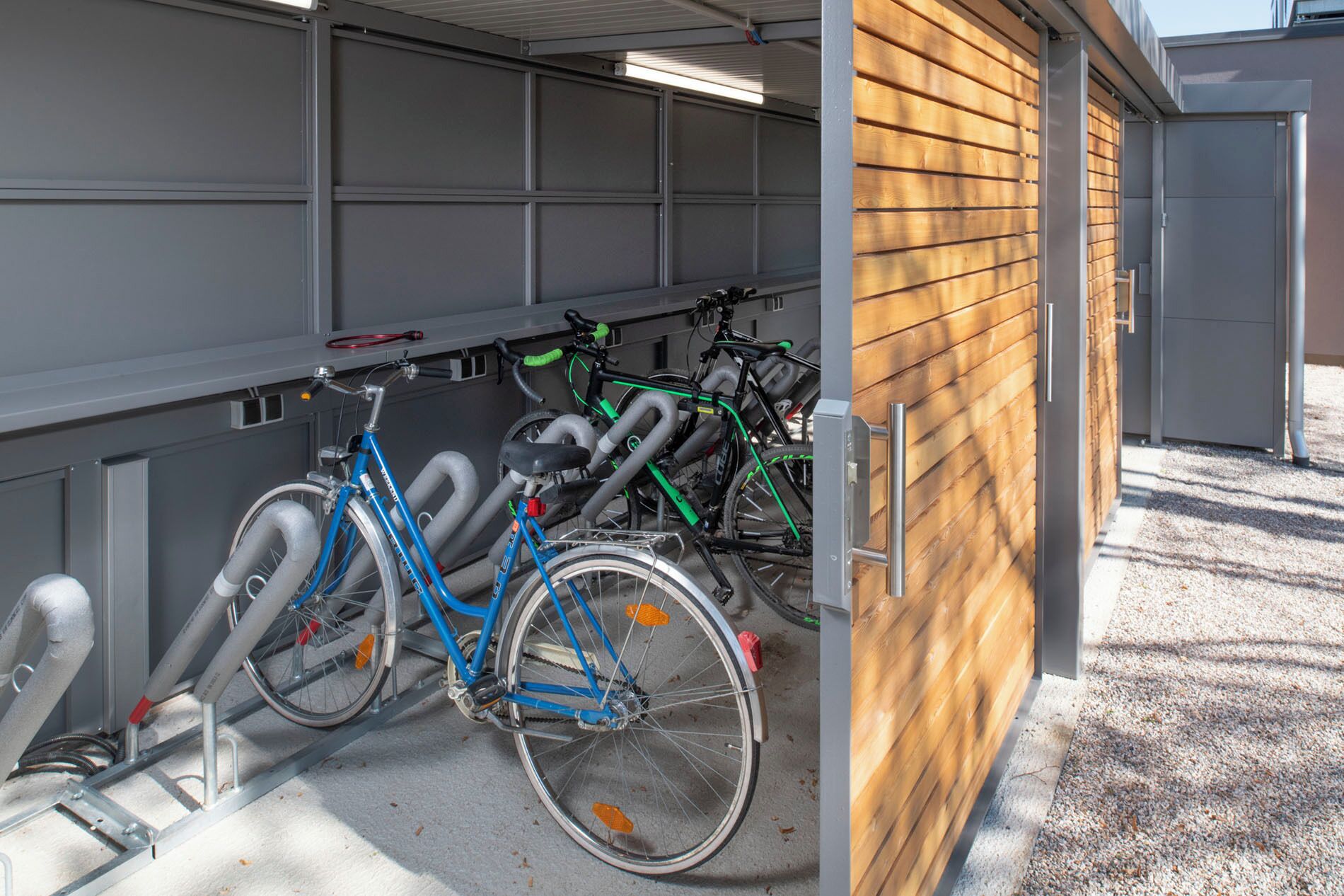 A bicycle parking area with a grey metal structure and a wooden wall.