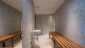 A modern bathroom with a wooden bench, a sink, and a mirror. - Hotel Le Parc (Wiener Neustadt)