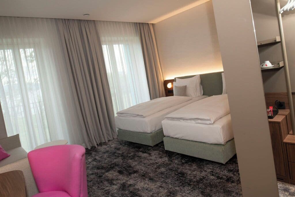 A hotel room with two beds, a desk, and a chair.