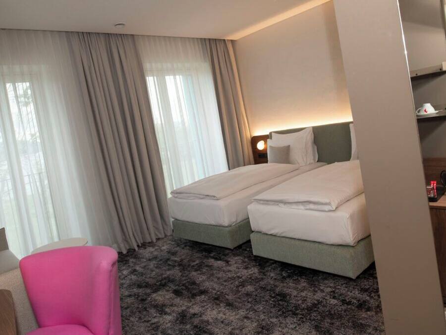 A hotel room with two beds, a desk, and a chair.