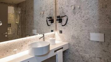 A modern bathroom with a large mirror, a round sink, and a shower.