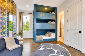 A room with a sofa, a blue bunk bed, a patterned rug, and a window with curtains. - Nashville getaway: rooftop hot tub, game room & bunk beds, sleeps 12 (Nashville)