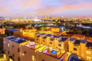 A modern hotel with rooftop terraces, a city skyline view, and a river in the background.