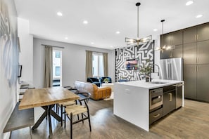 Enjoy a spacious living area with a dining table and comfortable seating, a well-equipped kitchen with a sleek island and sink.