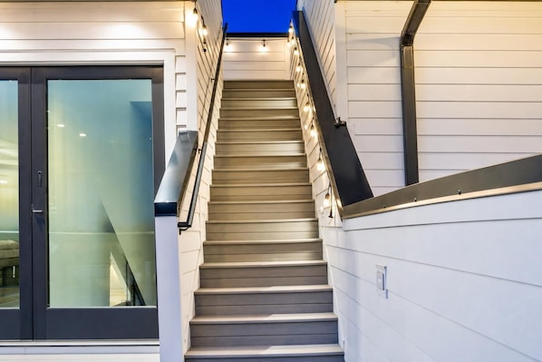 A staircase with a modern design, leading to a glass door entrance.
