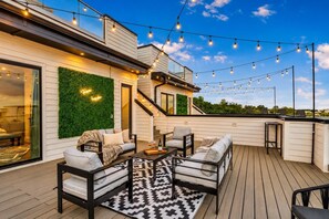 An outdoor deck with a sofa, chairs, and a coffee table, string lights, and a staircase. - Nashville group house with hot tub deck, game room & makeup bar, sleeps 12 (Nashville)