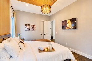 A modern hotel room with a large bed, a wooden headboard, a chandelier, and artwork on the walls. - Fall in Nashville: hot tub, game room house sleeps 12 near downtown (Nashville)