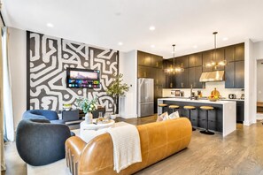 A modern kitchen with dark cabinetry, stainless steel appliances, and a central island with stools. - Nashville getaway: rooftop hot tub, game room & bunk beds, sleeps 12 (Nashville)