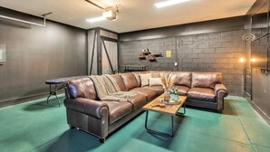 A modern living room with a leather sectional sofa, a wooden coffee table, and a brick accent wall. - Nashville hot tub getaway with poker room, sleeps 12, minutes from downtown (Nashville)