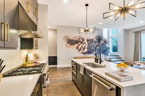 A modern kitchen with a central island, stainless steel appliances, and a unique wall mural. - Nashville weekend getaway: hot tub, poker room, sleeps 12 near Broadway (Nashville)