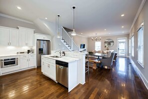 Una cocina amplia con armarios blancos, electrodomésticos de acero inoxidable y una isla central.