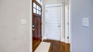 A hallway with a wooden door, a white door, and a doormat. - Fall Nashville weekend house with hot tub, mini golf & game room, sleeps 12 (Nashville)