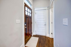 A hallway with a wooden door, a white door, and a doormat. - Nashville hot tub, mini golf & game room house, sleeps 12 (Nashville)