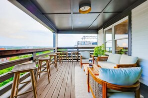 A covered outdoor deck with wooden furniture, a sofa, and a view of the cityscape. - Nashville house with hot tub, game room & theme room, sleeps 12 (Nashville)
