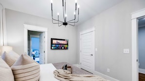 A bedroom with a bed, a TV mounted on the wall, and a door leading to another room. - Fall Nashville weekend house with hot tub, mini golf & game room, sleeps 12 (Nashville)