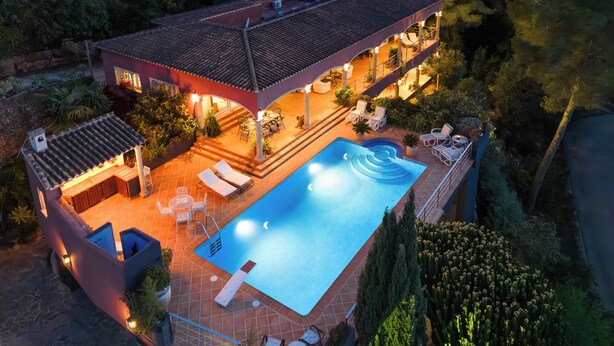 A two-story house with a swimming pool, outdoor seating, and a covered patio area.