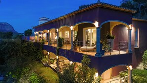 A multi-story building with a balcony, arched windows, and outdoor lighting.