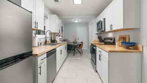 Una cocina moderna con armarios blancos, electrodomésticos de acero inoxidable y encimera de madera.