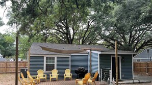 Un espacio de patio techado con mobiliario exterior y una parrilla.