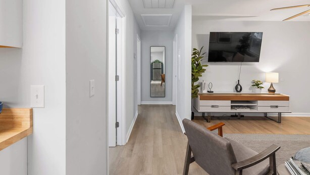 Una sala moderna con un televisor de pantalla plana, una mesa consola de madera y una zona de estar.